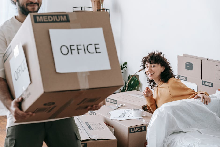 A person in casual clothing, partly visible, is holding a large cardboard box labeled 'OFFICE' with a 'MEDIUM' size indicator, as part of a home relocation or office move process facilitated by Remova