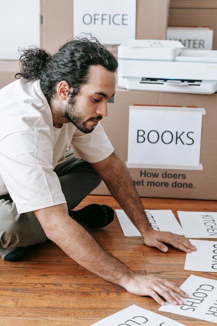 A person in casual clothing, partly visible, is holding a large cardboard box labeled 'OFFICE' with a 'MEDIUM' size indicator, as part of a home relocation or office move process facilitated by Remova